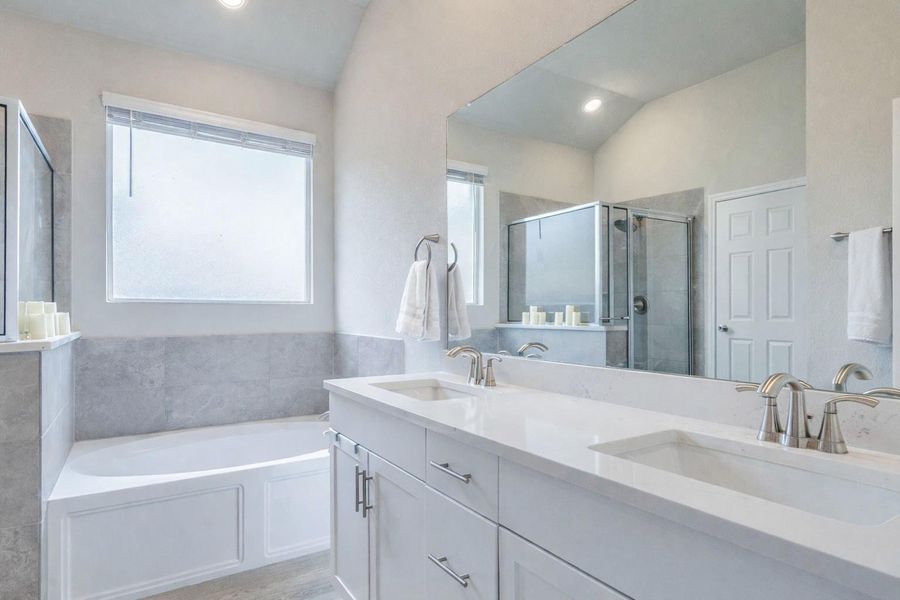 Indulge in a primary bathroom featuring a spacious built-in tub and a dual-sink vanity.