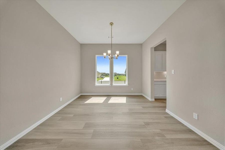 Unfurnished dining area featuring a chandelier and light wood-style flooring Unfurnished dining area featuring a chandelier and light wood-style flooring