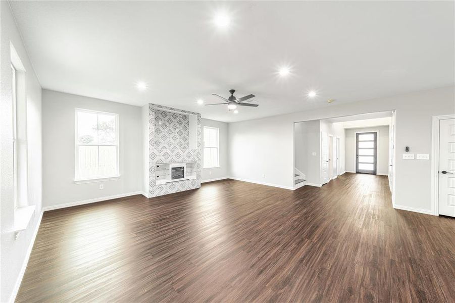 Unfurnished living room featuring dark wood-type flooring, healthy amount of natural light, a ceiling fan, and recessed lighting