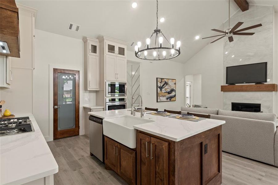Kitchen featuring stainless steel appliances, a sink, open floor plan, light wood-style floors, and white cabinetry