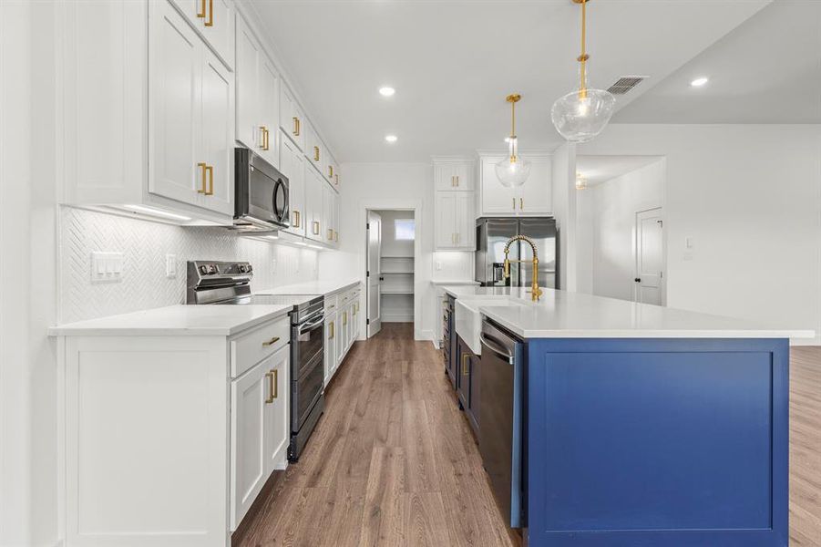 Kitchen featuring stainless steel appliances, light wood-style floors, white cabinetry, light countertops, and recessed lighting