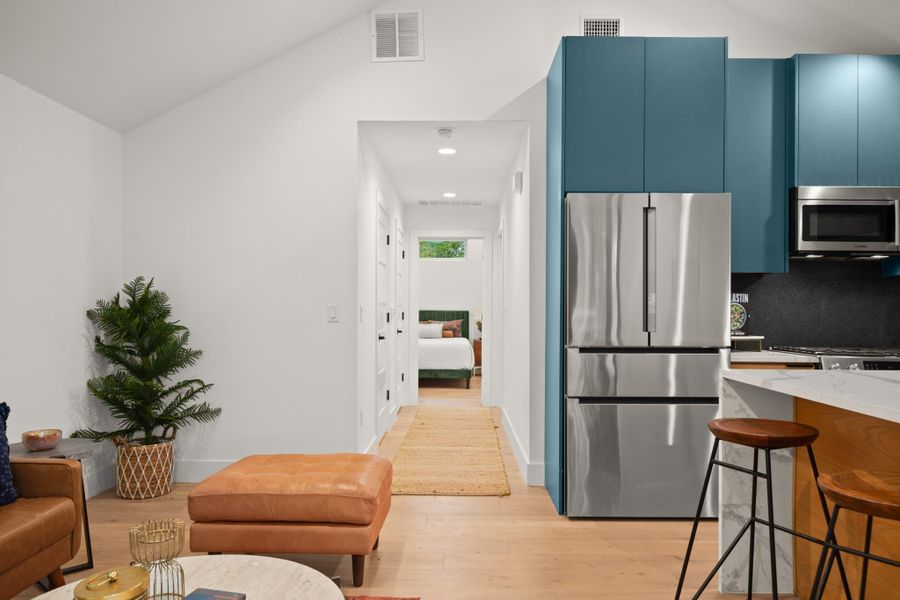 Kitchen featuring blue cabinets, appliances with stainless steel finishes, light stone countertops, light wood-style floors, and modern cabinets