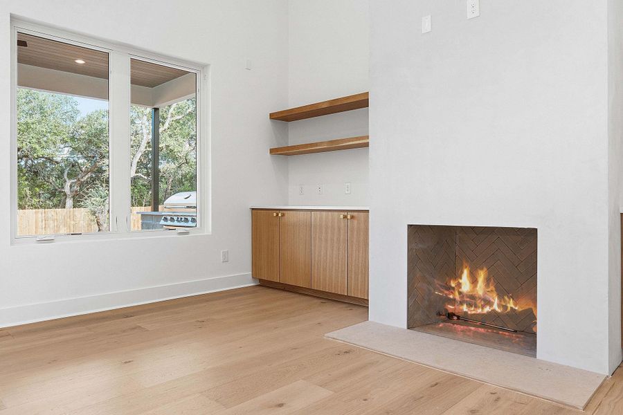 Warm hardwood flooring and built-in shelving complement a sleek hearth in this inviting room.