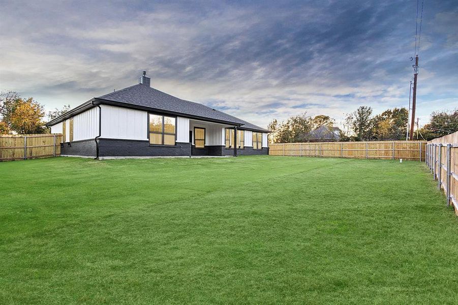 Back of property featuring a fenced backyard, brick siding, a patio area, a chimney, and a shingled roof
