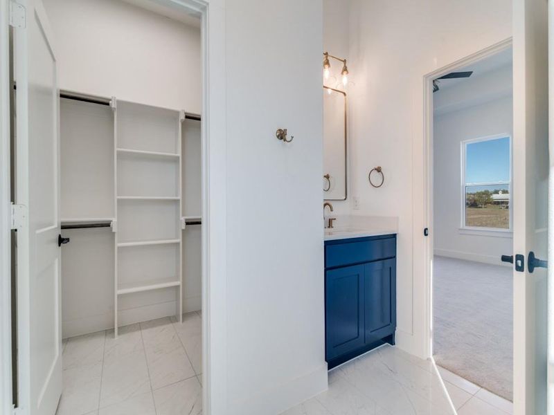 Bathroom featuring light marble finish flooring, vanity, and a spacious closet