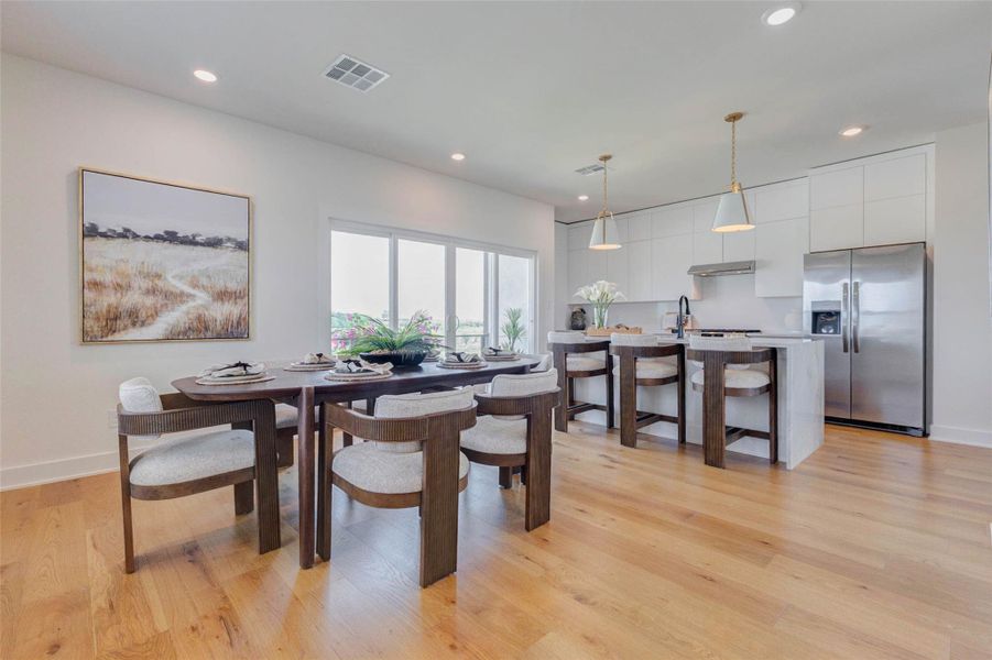 The dining area seamlessly connects to the kitchen, creating an open-concept space ideal for gatherings and everyday living. Large windows and sliding glass doors fill the room with natural light while offering views of the outdoor space. The layout provides plenty of room for entertaining, with a comfortable flow that makes hosting both easy and enjoyable. The picture shown is from the model home with the same floor plan, Rev floor plan.
