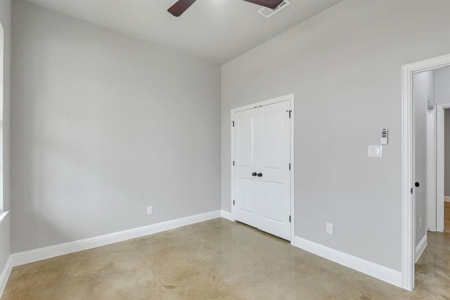 Unfurnished bedroom featuring concrete floors, a closet, and a ceiling fan