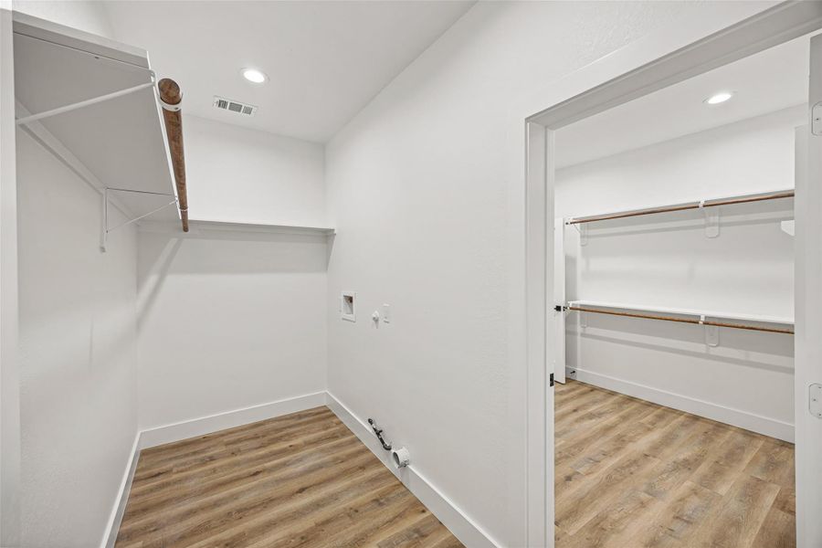 Dedicated utility room with washer/dryer connections and built-in hanging rod.