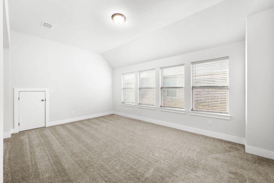 A spacious room offers comfortable carpet flooring and multiple windows, providing a serene ambiance.