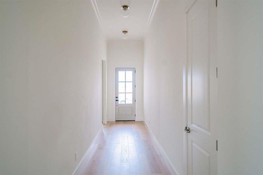 Hall with light hardwood / wood-style floors and ornamental molding