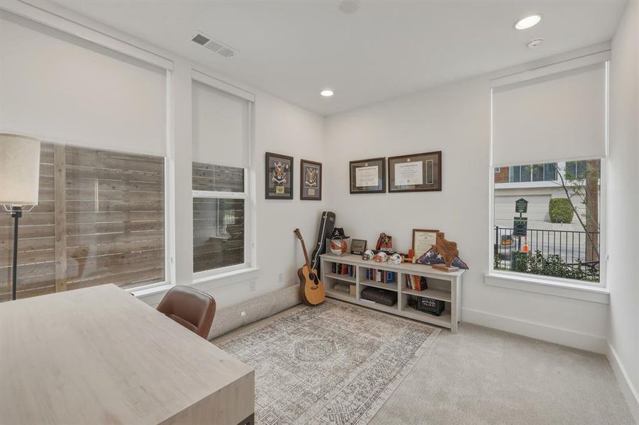 Home office with light colored carpet and recessed lighting