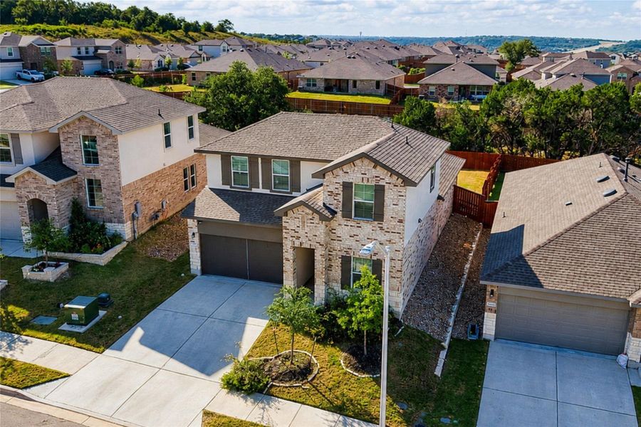 Aerial view of home featuring a striking modern home with a brick and stone facade welcomes with an inviting entryway and integrated garage.