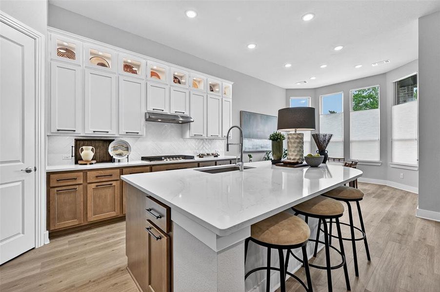 Kitchen featuring stovetop, under cabinet range hood, light wood-style floors, recessed lighting, and tasteful backsplash Kitchen featuring stovetop, under cabinet range hood, light wood-style floors, recessed lighting, and tasteful backsplash