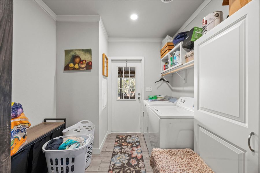 Laundry area featuring ornamental molding and washing machine and dryer