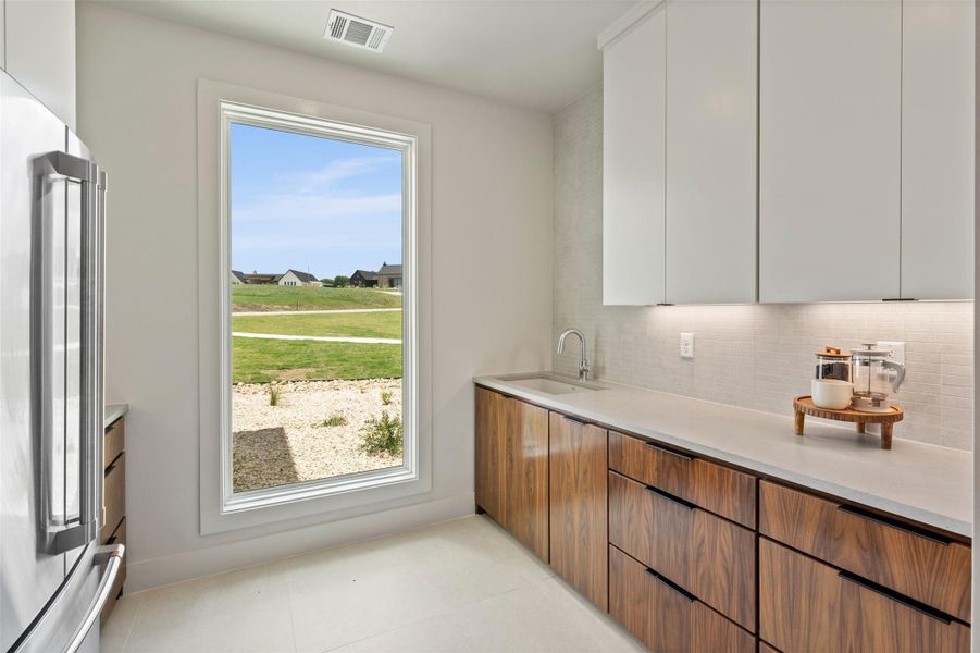 Kitchen with stainless steel fridge, brown cabinetry, modern cabinets, and tasteful backsplash