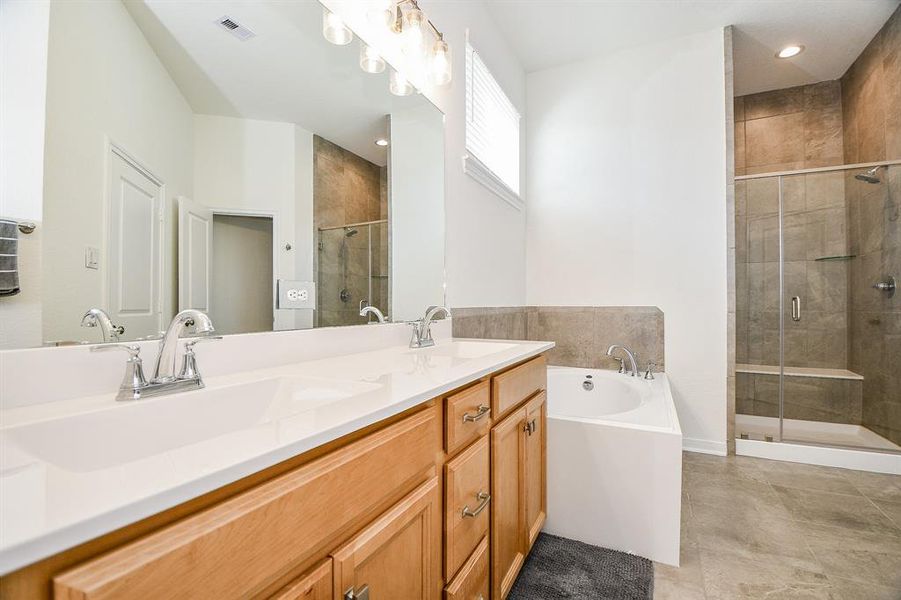 The dual sink vanity offers ample storage for all the necessities, while the mirror and modern vanity lights above create a bright and polished look.