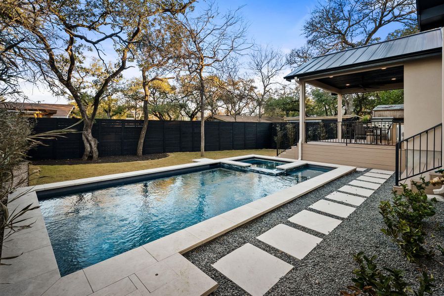 Combined pool / hot tub with a fenced backyard and a patio area
