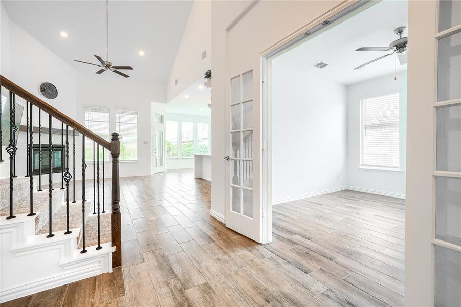 Corridor featuring light wood-style floors, recessed lighting, healthy amount of natural light, stairway, and high vaulted ceiling Corridor featuring light wood-style floors, recessed lighting, healthy amount of natural light, stairway, and high vaulted ceiling