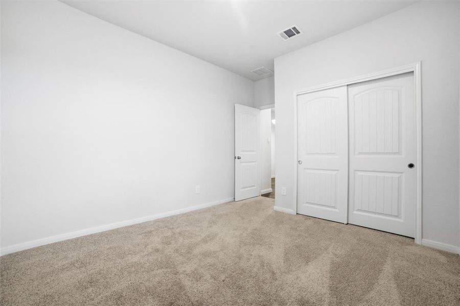 Unfurnished bedroom with light colored carpet and a closet Unfurnished bedroom with light colored carpet and a closet
