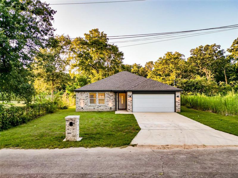 Ranch-style home featuring roof with shingles, concrete driveway, an attached garage, brick siding, and a front yard Ranch-style home featuring roof with shingles, concrete driveway, an attached garage, brick siding, and a front yard