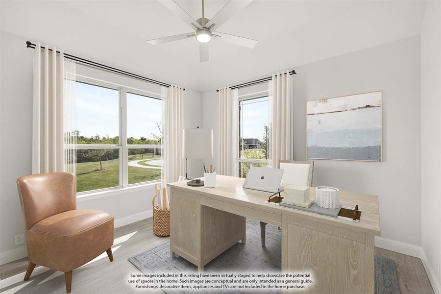 Home office with light wood desk, ceiling fan, hardwood floors, and large windows with backyard views