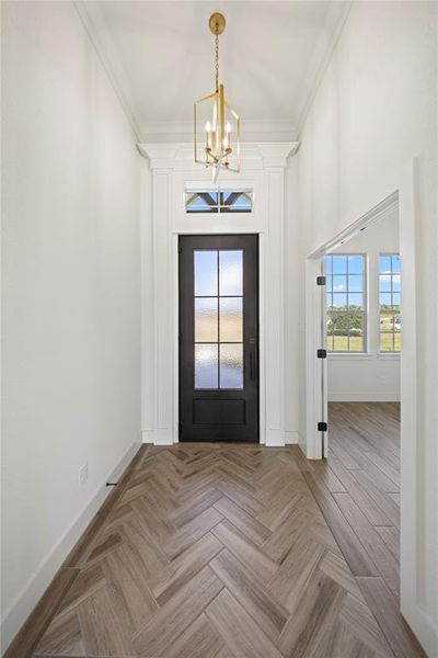 Foyer entrance with ornamental molding and a chandelier