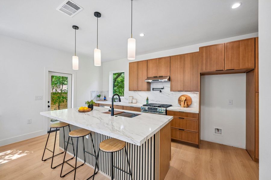 A well-lit kitchen with sleek wooden cabinetry and a quartz island perfect for entertaining. A well-lit kitchen with sleek wooden cabinetry and a quartz island perfect for entertaining.