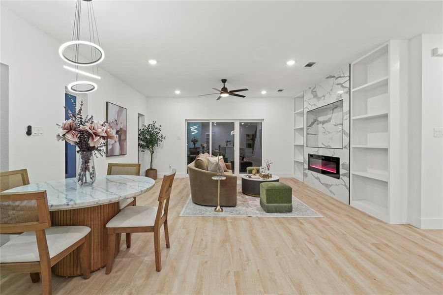 Dining area with built in shelves, a premium fireplace, light wood finished floors, a ceiling fan, and recessed lighting Dining area with built in shelves, a premium fireplace, light wood finished floors, a ceiling fan, and recessed lighting