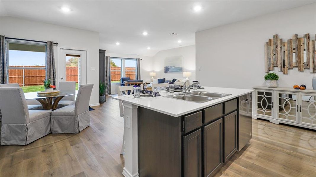 Kitchen featuring dark wood finish cabinetry, light countertops, open floor plan, lofted ceiling, and an island with sink Kitchen featuring dark wood finish cabinetry, light countertops, open floor plan, lofted ceiling, and an island with sink