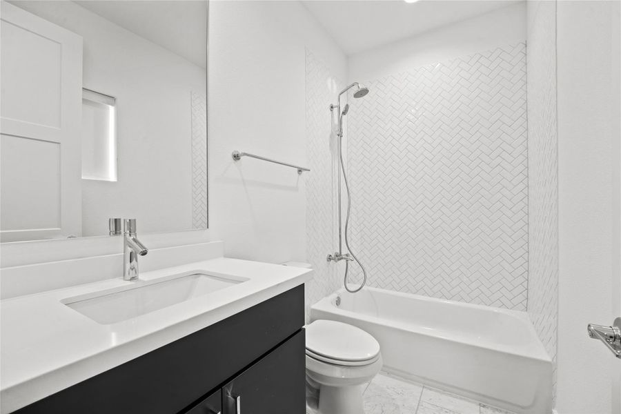 Bathroom featuring a white subway tile shower surround with a herringbone pattern, a chrome shower fixture, a built-in bathtub, a vanity with a white countertop and integrated sink, and a chrome single-handle faucet