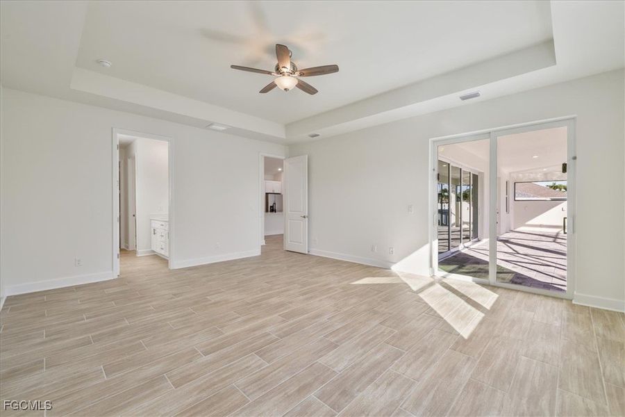 Unfurnished room featuring a tray ceiling, a ceiling fan, and wood finish floors