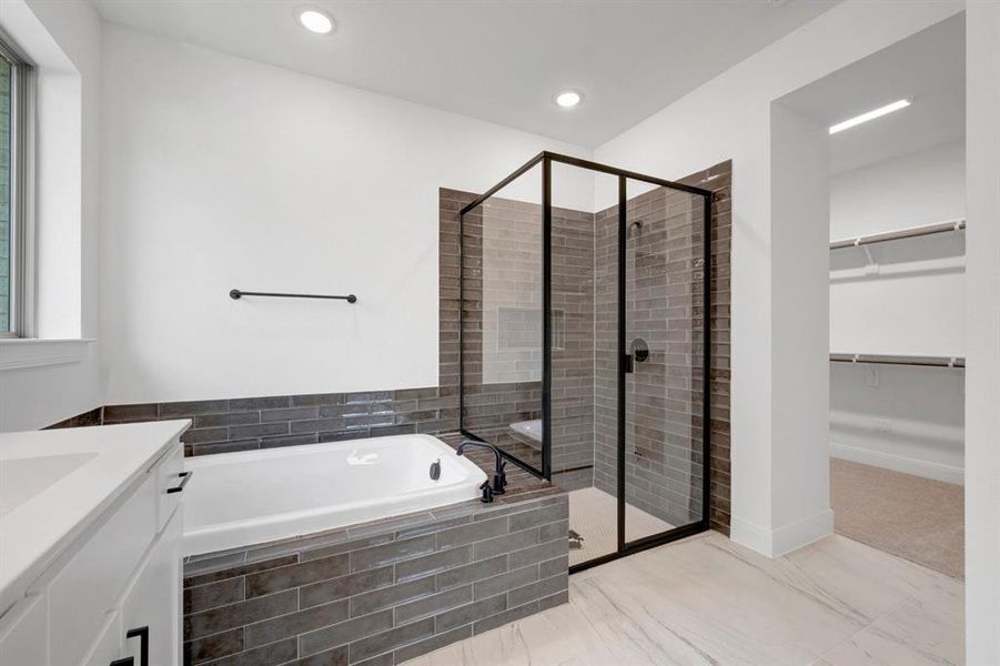 Contemporary bathroom featuring a freestanding tub with dark tile surround, a glass-enclosed shower with contrasting tile, and a single vanity with white cabinetry