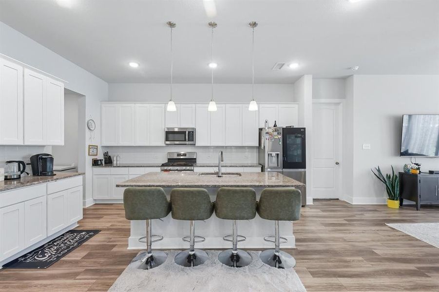 Kitchen featuring a breakfast bar, light stone countertops, decorative light fixtures, backsplash, and recessed lighting Kitchen featuring a breakfast bar, light stone countertops, decorative light fixtures, backsplash, and recessed lighting