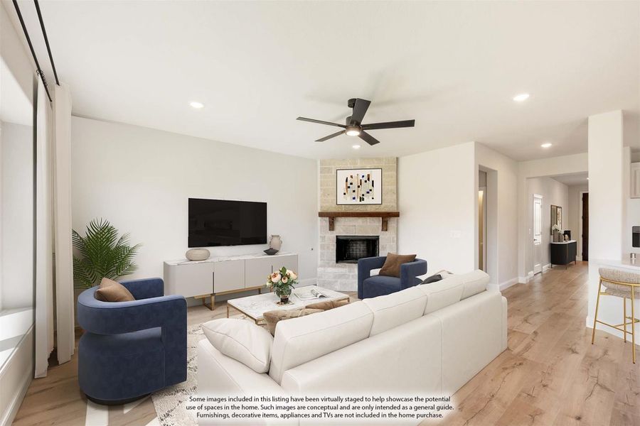 Living room with stone fireplace, ceiling fan, hardwood floors, and white sofa with blue accent chairs