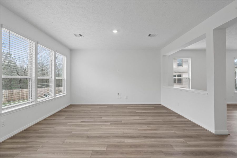Relax and unwind in this cozy family room, featuring high ceilings, ceiling fan with lighting, recessed lighting, and a wall of large windows with privacy blinds that provides natural light.