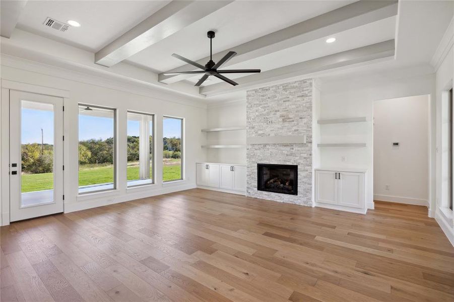 Unfurnished living room featuring ceiling fan, a stone fireplace, and light wood-type flooring