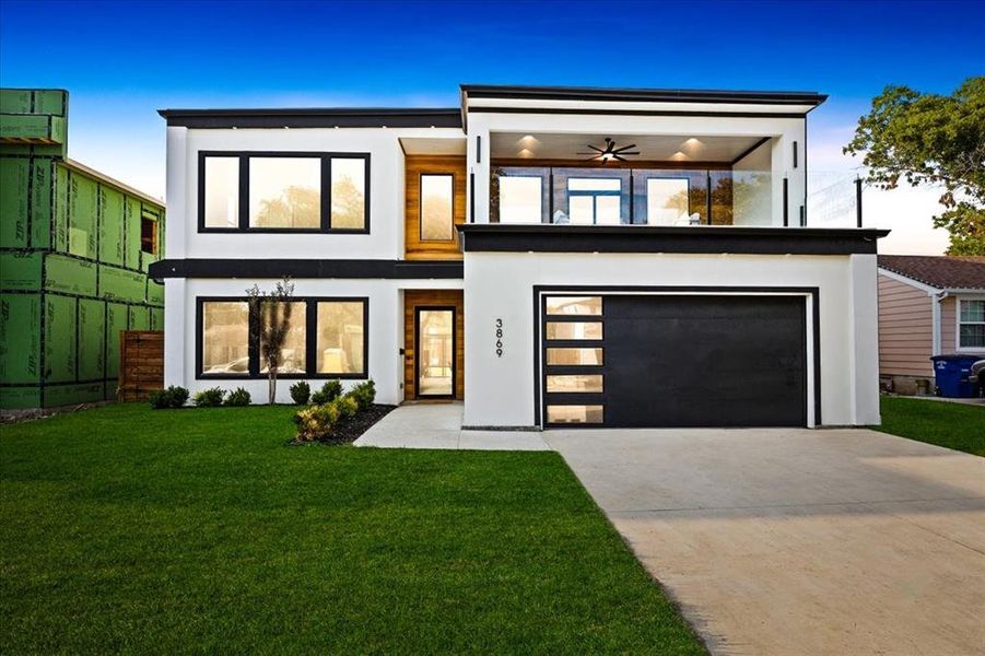 View of front of home with a garage, a front lawn, and ceiling fan