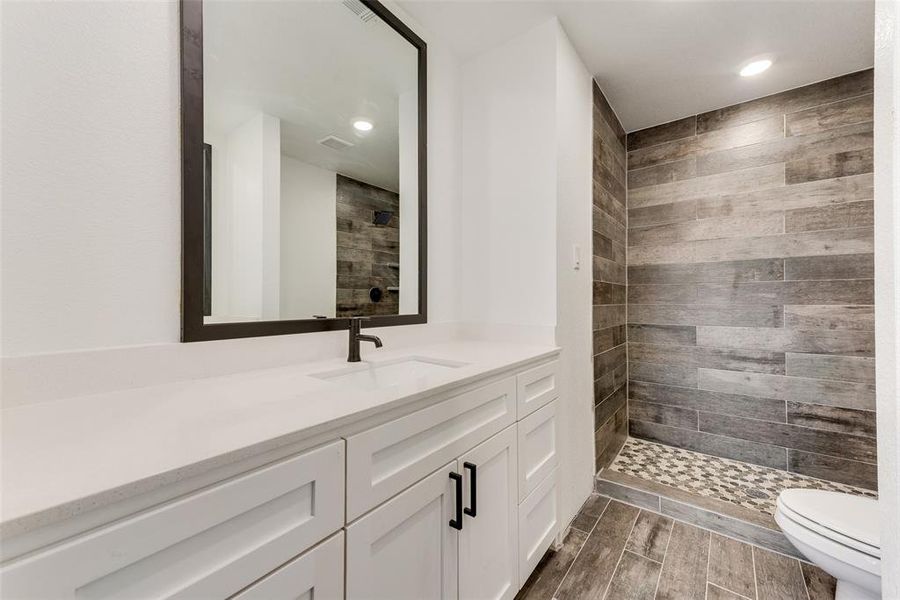 Bathroom featuring vanity, toilet, and a tile shower