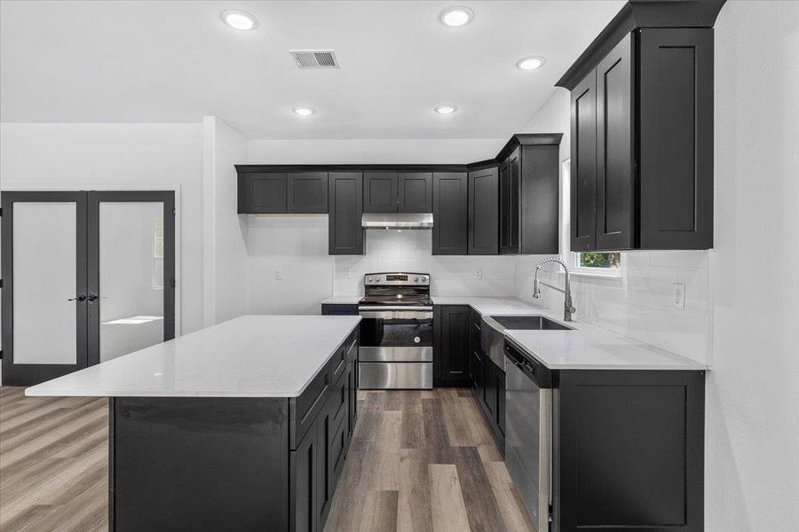 Sleek dark cabinetry and stone countertops anchor this modern culinary space with a central island. Sleek dark cabinetry and stone countertops anchor this modern culinary space with a central island.