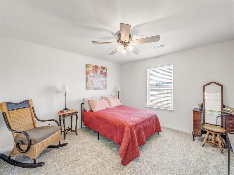 Bedroom with light colored carpet and a ceiling fan