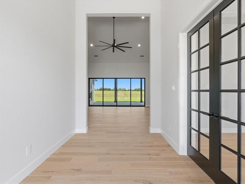 Entryway with light wood-finish flooring, white walls, and black-framed glass French doors