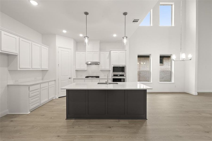 Kitchen with a sink, appliances with stainless steel finishes, baseboards, light countertops, and white cabinetry