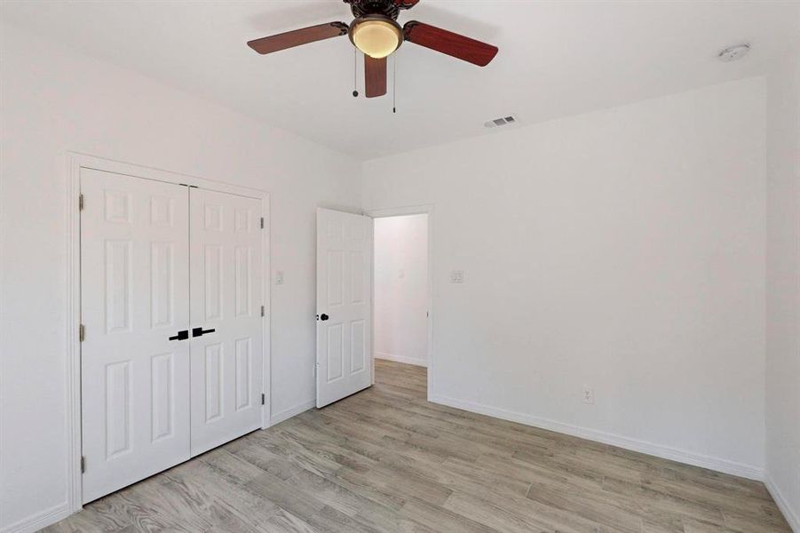 Unfurnished bedroom with ceiling fan, a closet, and light wood-type flooring