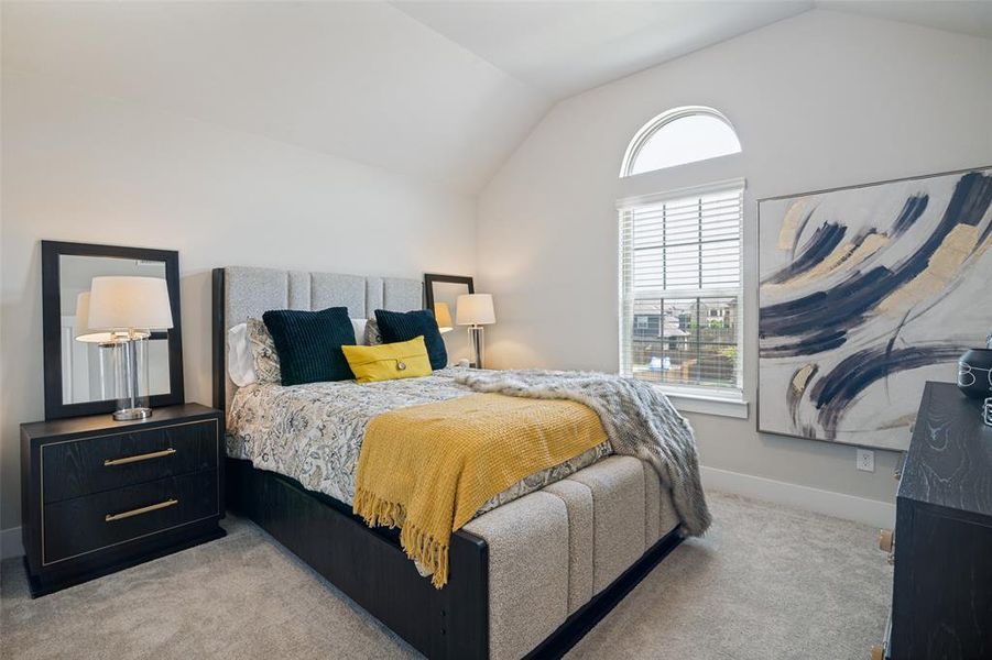 Vaulted ceiling bedroom with arched window, carpet flooring, a paneled upholstered headboard, and built-in window blinds