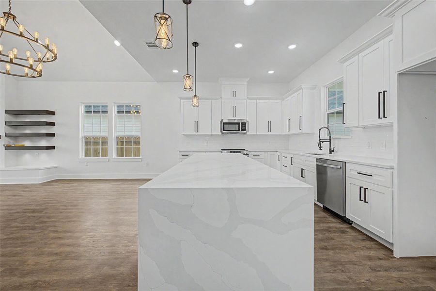 Large island with waterfall-style counter detail, pendant lighting, and plenty of prep and gathering space.