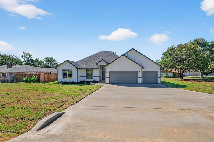 Modern farmhouse style home with concrete driveway, a garage, and a shingled roof