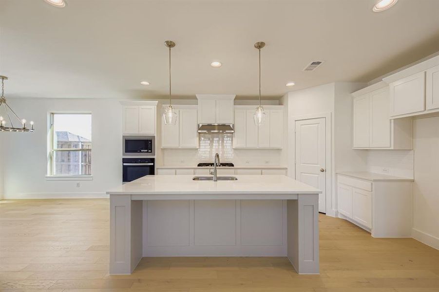 Kitchen with hanging light fixtures, white cabinetry, tasteful backsplash, wall oven, and recessed lighting Kitchen with hanging light fixtures, white cabinetry, tasteful backsplash, wall oven, and recessed lighting