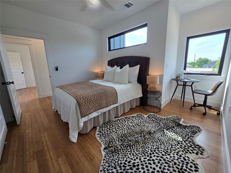 Bedroom featuring wood finished floors, visible vents, a ceiling fan, and baseboards Bedroom featuring wood finished floors, visible vents, a ceiling fan, and baseboards