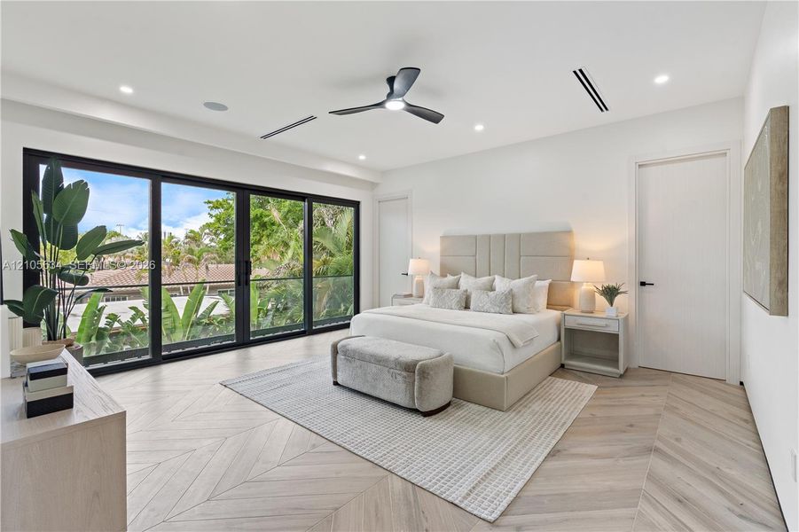 Interior space featuring chevron-patterned wood-finish flooring, floor-to-ceiling multi-panel sliding glass doors, recessed lighting, and a modern black ceiling fan
