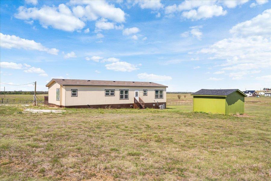 Back of house with a yard, a storage shed, and a rural view Back of house with a yard, a storage shed, and a rural view